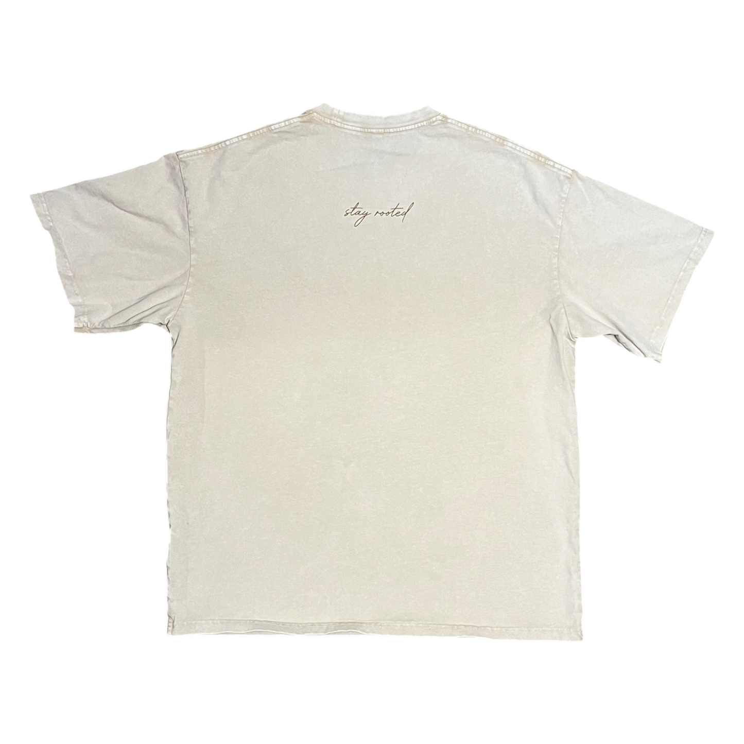 A light beige crewneck t-shirt shown from the back, featuring a small cursive 'stay rooted' logo printed near the upper center back.