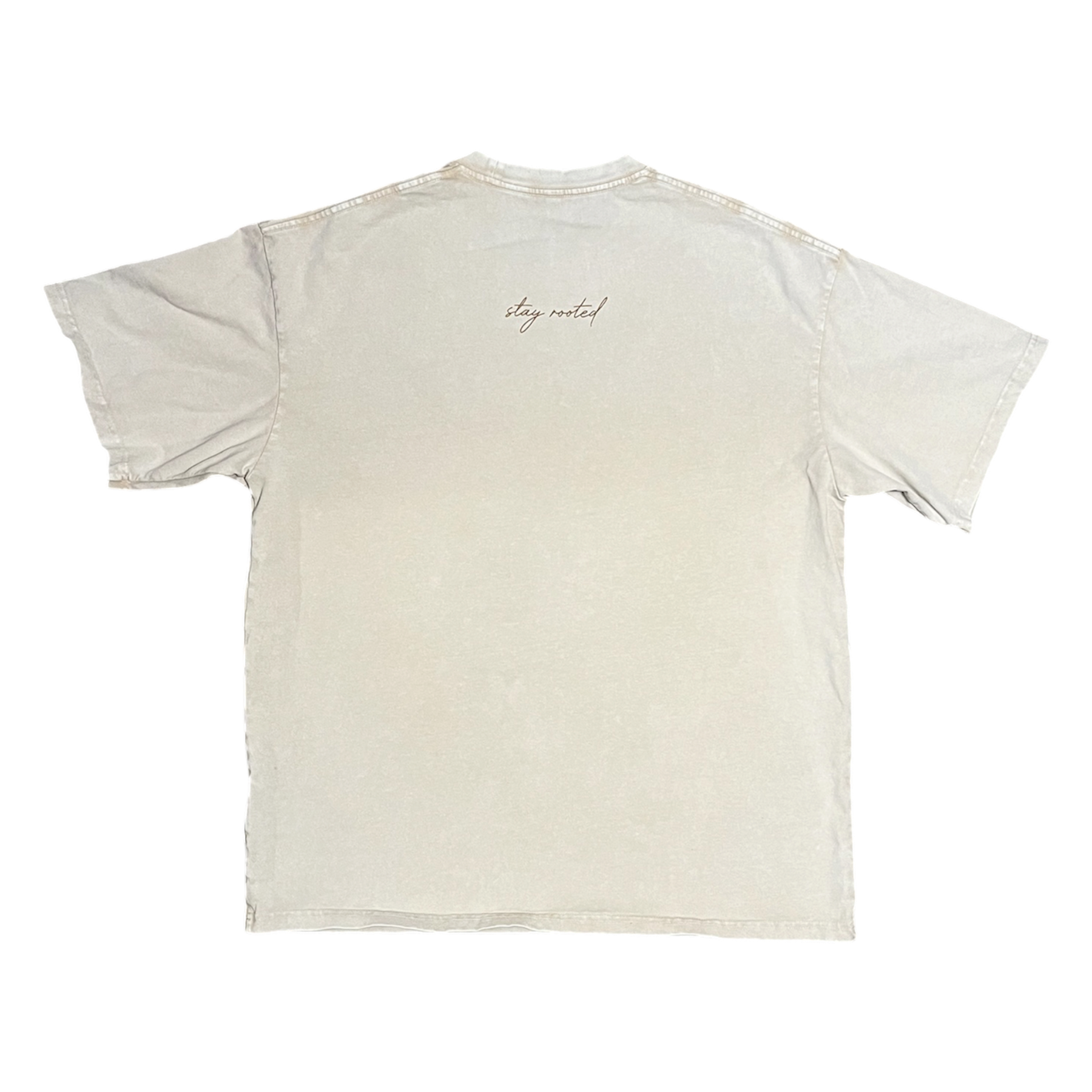 A light beige crewneck t-shirt shown from the back, featuring a small cursive 'stay rooted' logo printed near the upper center back.
